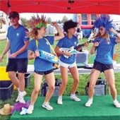 Four teen recreation aides dance under a tent outside at an event.