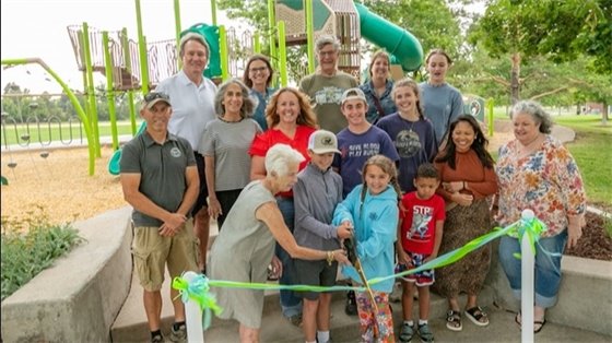 Residents join Mayor Lantz to cut the ribbon for the new playground.