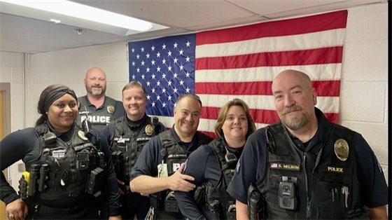 Greenwood Village School Resource Officers pose in front of a U.S. flag.
