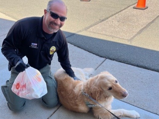 Det.  Tony Costarella gives a dog a treat during Drug Take Back Day