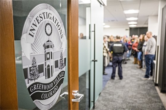 GVPD police investigations logo on an open door, with citizens being given a tour of the department in the background.