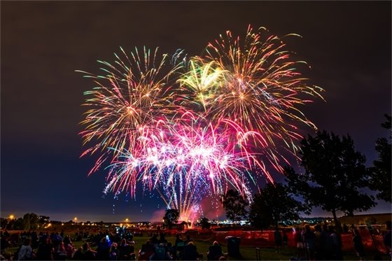 Fireworks over Village Greens Park with Greenwood Village Day attendees looking on.