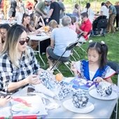 Adult and child making pumpkin crafts with additional crafting tables in the background.