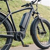 Electric bike on a trail near a grassy hill.