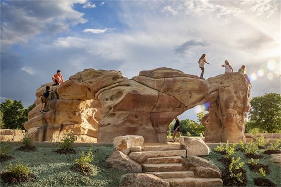 Children play on natural play structure in Village Greens North