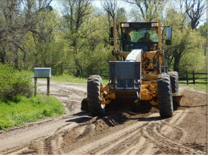 Grading machine grading a dirt road