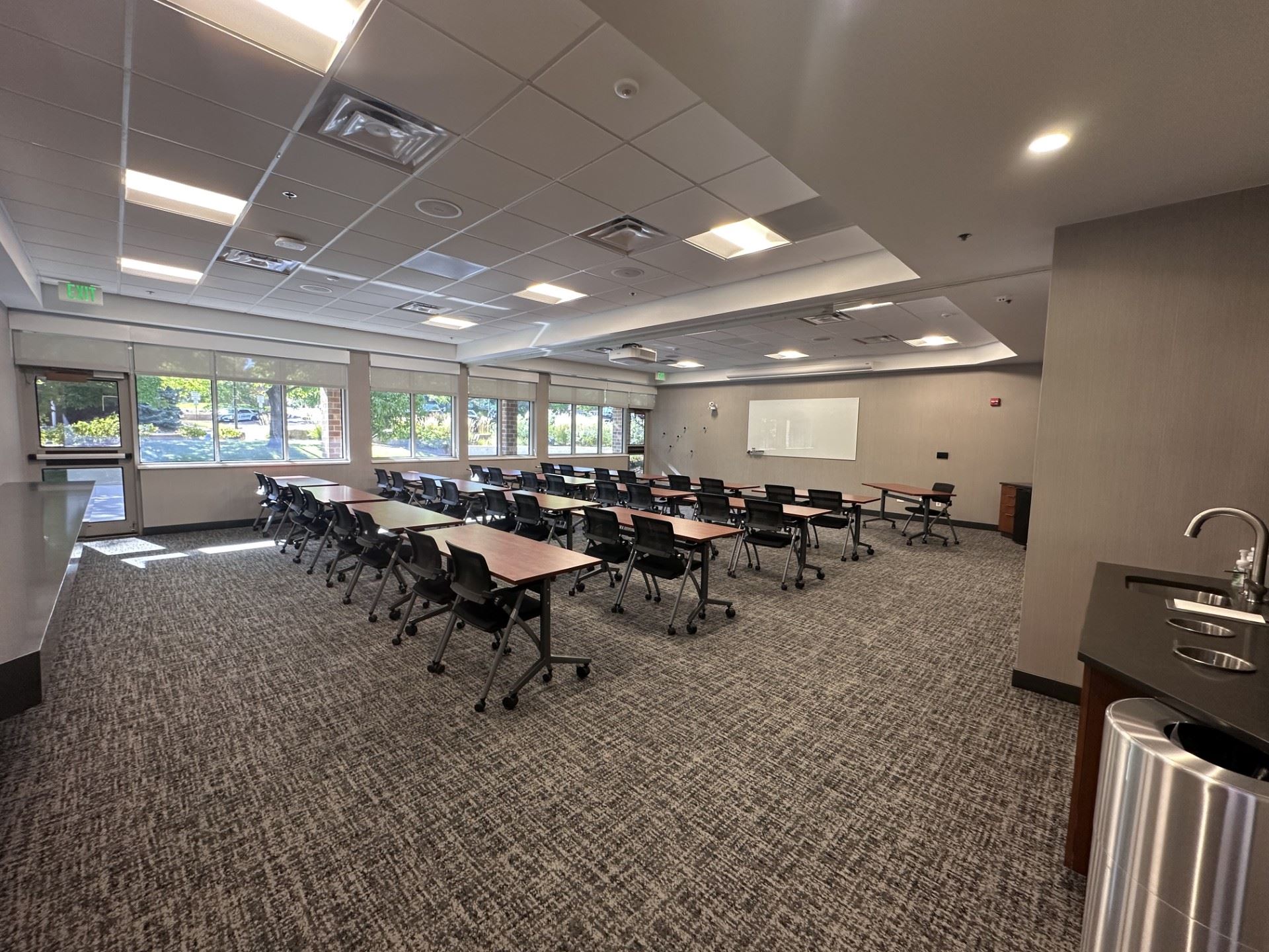 Large open room with tables and chairs facing a white board